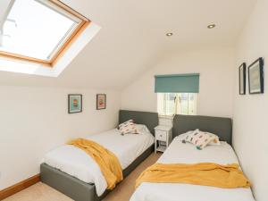 two beds in a room with a window at 2 Dewars Farm Cottages in Bicester
