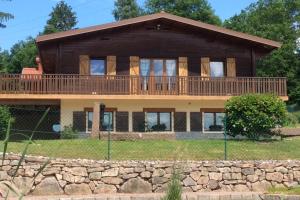 a large house with a large deck and a stone wall at Le Chalet du Cerf au coeur du Massif des Vosges, proche Gérardmer et Alsace in Gerbépal