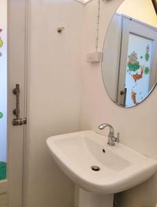 ein Badezimmer mit einem weißen Waschbecken und einem Spiegel in der Unterkunft บ้านไร่นายสิงห์-Banrainaysing in Ban Huai Khai