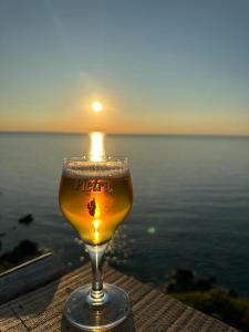 a glass of beer sitting on a table near the water at Corse Balagne Les Terrasses de Lozari secteur Ile Rousse in Belgodère
