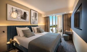 a hotel room with a large bed and a desk at Aminess Vival Maestral Hotel in Novigrad Istria