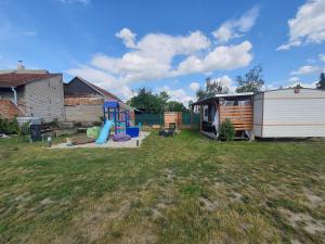 un patio trasero con una caravana y un parque infantil en Mobilheim v LVA 1, en Podivín