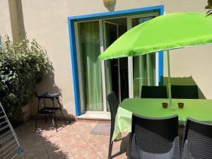 a table with a green umbrella on a patio at Corse Balagne Les Terrasses de Lozari secteur Ile Rousse in Belgodère