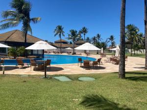 弗烈歇德斯的住宿－Bangalô Eco Residence Flecheiras，一个带桌椅和遮阳伞的游泳池