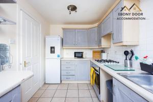 a kitchen with blue cabinets and a white refrigerator at Ebony Door Accommodation Charming 3 Bedroom House Thurrock Sleeps 6 in Grays Thurrock