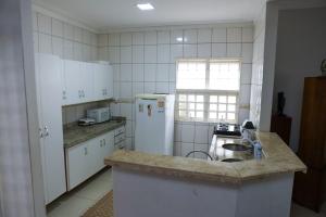 a kitchen with a sink and a white refrigerator at Pousada dos Bosques - Refúgio Urbano in Cuiabá