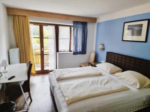 1 Schlafzimmer mit 2 Betten, einem Tisch und einem Fenster in der Unterkunft Hotel Pfrontener Hof in Pfronten