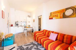 a living room with a orange couch and a kitchen at LA RESERVE AP4369 By Riviera Holiday Homes in Villefranche-sur-Mer