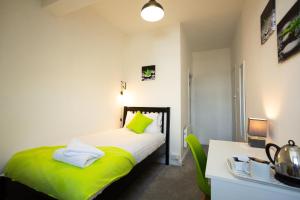 a bedroom with a bed with green sheets and a desk at The Sea Lynn in Morecambe