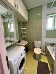 a bathroom with a toilet a sink and a washing machine at Color Apartments Nicolae Tonitza St in Bucharest