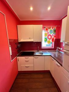 a kitchen with red walls and white cabinets and a sink at Color Apartments Nicolae Tonitza St in Bucharest