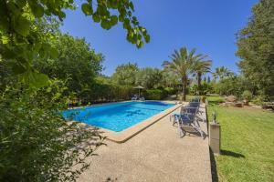 a swimming pool in a yard with chairs and trees at Villa Ca Na Rossa in Campanet