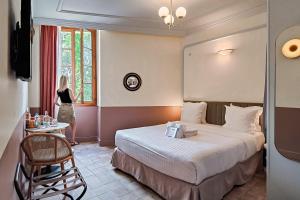 a woman standing in a hotel room with a bed at Aparthotel AMMI Vieux Nice in Nice