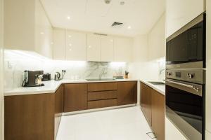 a kitchen with white counters and brown cabinets at Voyage 5 Star Mamsha With Ocean Views in Abu Dhabi