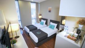 um quarto de hotel com duas camas e uma televisão em Homey AirPort Hotel em Arnavutköy
