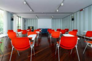 une chambre avec des chaises rouges, des tables et un écran dans l'établissement Hotel Crivi's, à Milan