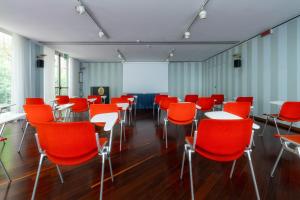 a room with red chairs and tables and a screen at Hotel Crivi's in Milan