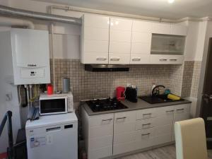 a kitchen with white cabinets and a stove and a microwave at Natura Slanic Moldova in Slănic-Moldova