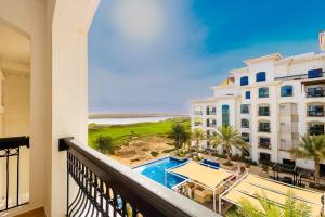 a balcony with a view of the beach and the ocean at Voyage Studio In Ansam With Golf Course View in Abu Dhabi