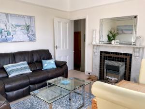The KinBrae Apartment في توركواي: غرفة معيشة مع أريكة جلدية ومدفأة