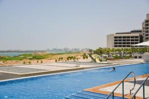 uma piscina num resort com praia e edifícios em Voyage One Bedroom In Mayan em Abu Dhabi