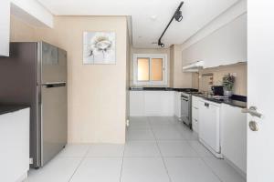 a large kitchen with white tile floors and appliances at Frank Porter - TECOM in Dubai