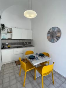 a kitchen with a table and chairs and a clock at Mana House in Maiori +5 photos