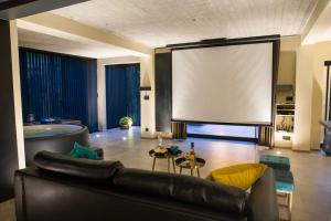 a living room with a couch and a large screen at Buenas Noches Villa Standing piscine & wellness in Boncelles