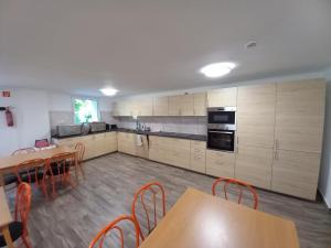 a kitchen with wooden cabinets and wooden tables and chairs at Márianosztrai Zarándokszálláshely in Márianosztra