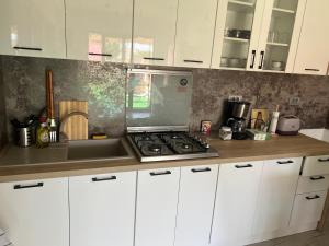 a kitchen with white cabinets and a stove top oven at Vila Alemary in Năvodari