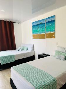 a bedroom with two beds and a picture of the beach at Hostal islamar in San Andrés