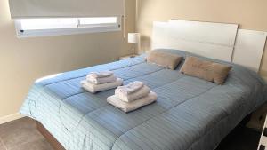 een slaapkamer met een blauw bed en handdoeken bij BARCELONA APARTS in San Luis