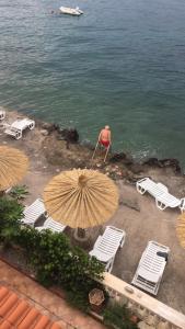 an umbrella and chairs and a man in the water at Apartments Palace Mira Mare in Tivat