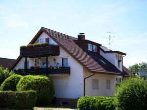 uma casa branca com uma varanda com flores em Ferienwohnung mit Garten em Ehrenkirchen