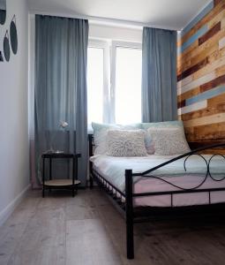 1 dormitorio con 1 cama con cabecero de madera y ventana en APARTAMENT "Opawska Przystań", en Głuchołazy