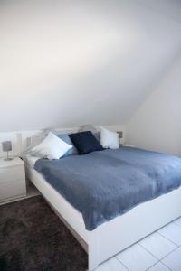 カロリーネンジールにあるFerienwohnung Mühlenblick 3の白いベッド(青いシーツ付)が備わるベッドルームです。
