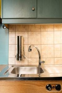 a kitchen sink with a faucet on a tiled wall at oscar city room in Athens