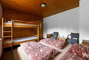 a bedroom with two bunk beds and two chairs at Penzion pod Pralesem in Velké Karlovice