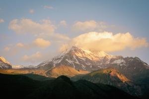 a snow covered mountain with clouds in the sky at Heaven Hill in Kazbegi