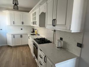 a white kitchen with white cabinets and a stove at Reis apart in Trabzon