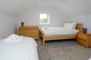a bedroom with two beds and a window at Primrose Cottage in Leiston
