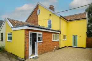 a yellow house with a brick at Primrose Cottage in Leiston