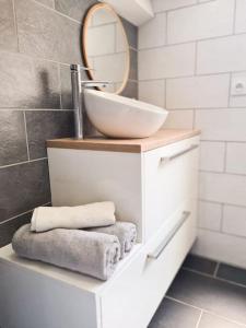 een badkamer met een wastafel, een spiegel en handdoeken bij Appartement avec terrasse proche Nice et Monaco in Contes