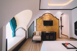 a room with a bed and a chair and a tv at Goldient Boutique Hotel in Da Lat