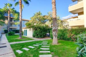 a garden with palm trees and a walkway at *Le Carpe Diem, Appartement 2 chambres, piscine, 2 Parking, Clim* in Montpellier