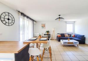 een woonkamer met een tafel en een klok aan de muur bij *Le Carpe Diem, Appartement 2 chambres, piscine, 2 Parking, Clim* in Montpellier