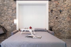 a bedroom with a bed with a table and a stone wall at Labiena 12 Lago maggiore in Laveno-Mombello