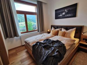 a bedroom with a bed with a blanket and a window at Das Wipferl - Dein Nest in den Bergen in Maria Luggau