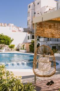 a rattan chair hanging over a swimming pool at Apartamentos Marian in San Antonio