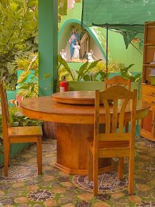 BARRIL GREEN HOMESTAY في Batuan: طاولة خشبية مع كرسيين و لوحة اريل
